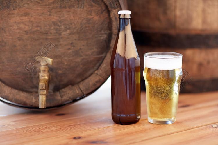 啤酒厂饮料和酒精的概念关闭旧啤酒桶玻璃和木制的桌子上的瓶子